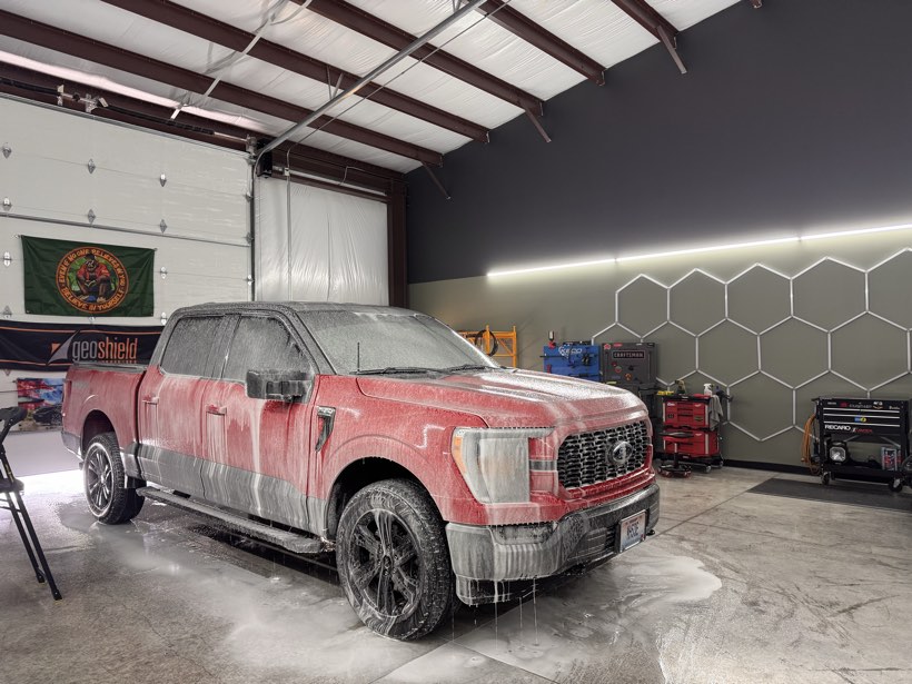Red Ford F-150 covered in thick snow foam during a prewash at The Auto Film Studio