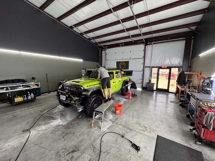 Wide view of The Auto Film Studio wash bay with a green Jeep Gladiator being detailed