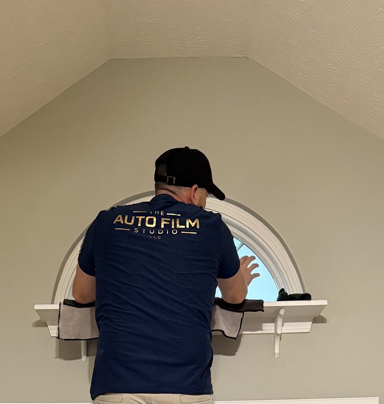 Auto Film Studio installer putting window film on an arched window inside a home