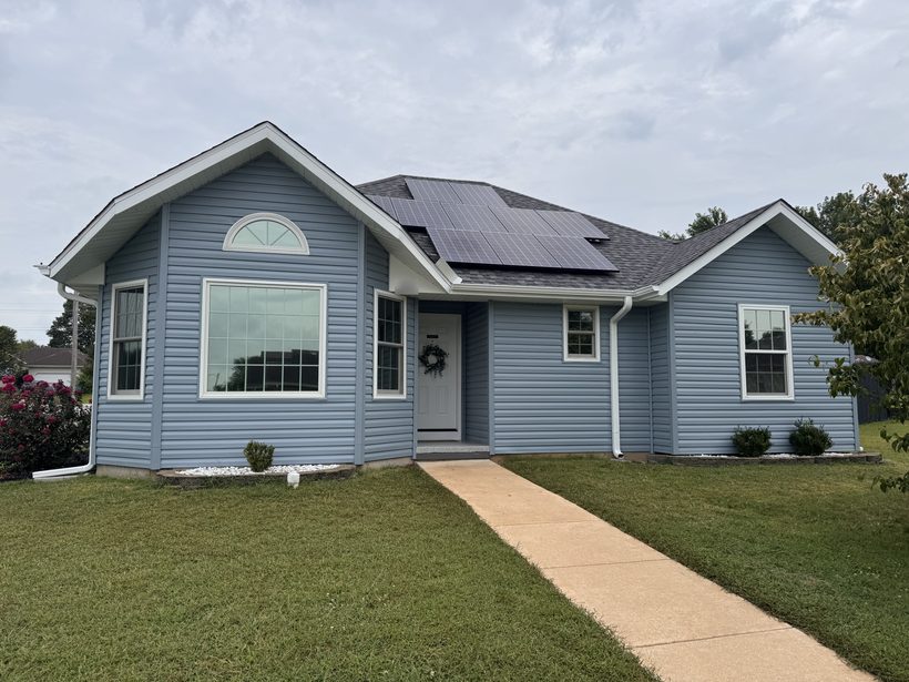Blue single-story home with tinted front windows, including the arched window over the bay window