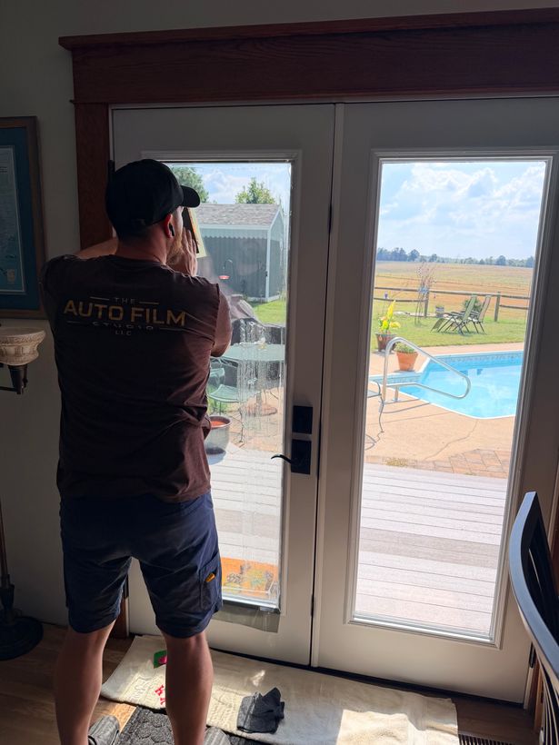 Auto Film Studio installer putting window film on a pair of glass patio doors inside a home
