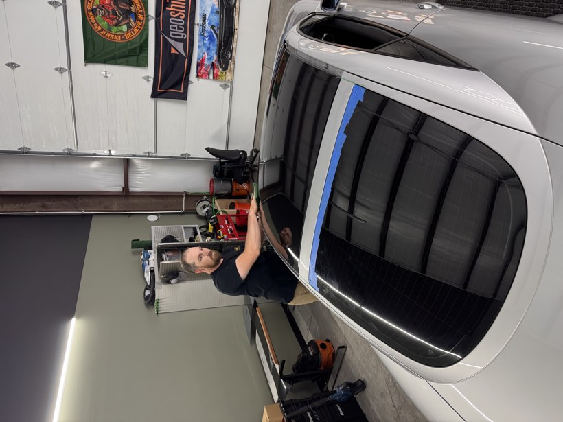 Vinyl roof wrap being worked across the curved roofline of a silver Audi at The Auto Film Studio