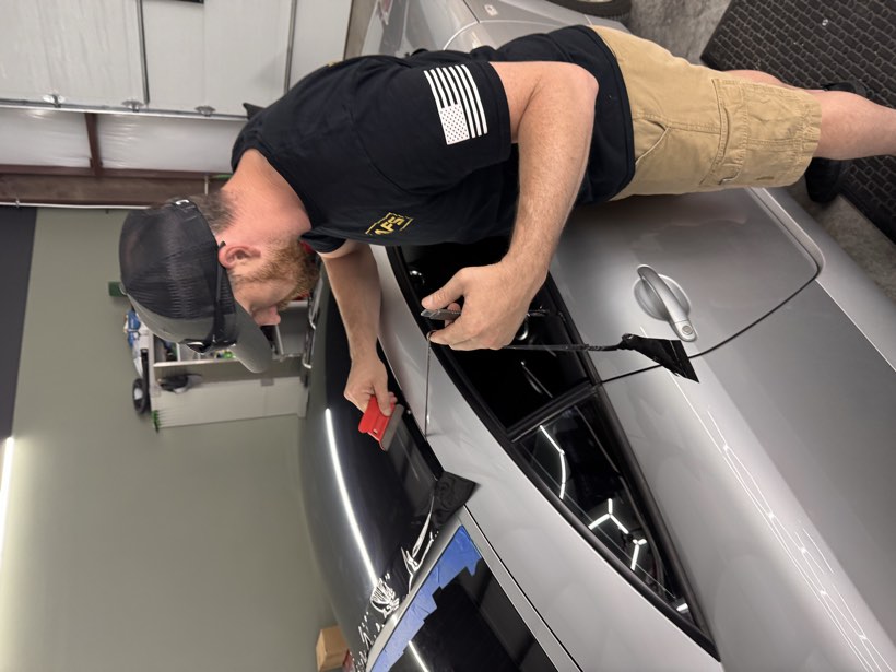 Justin applying a gloss black vinyl roof wrap to a silver Audi at The Auto Film Studio