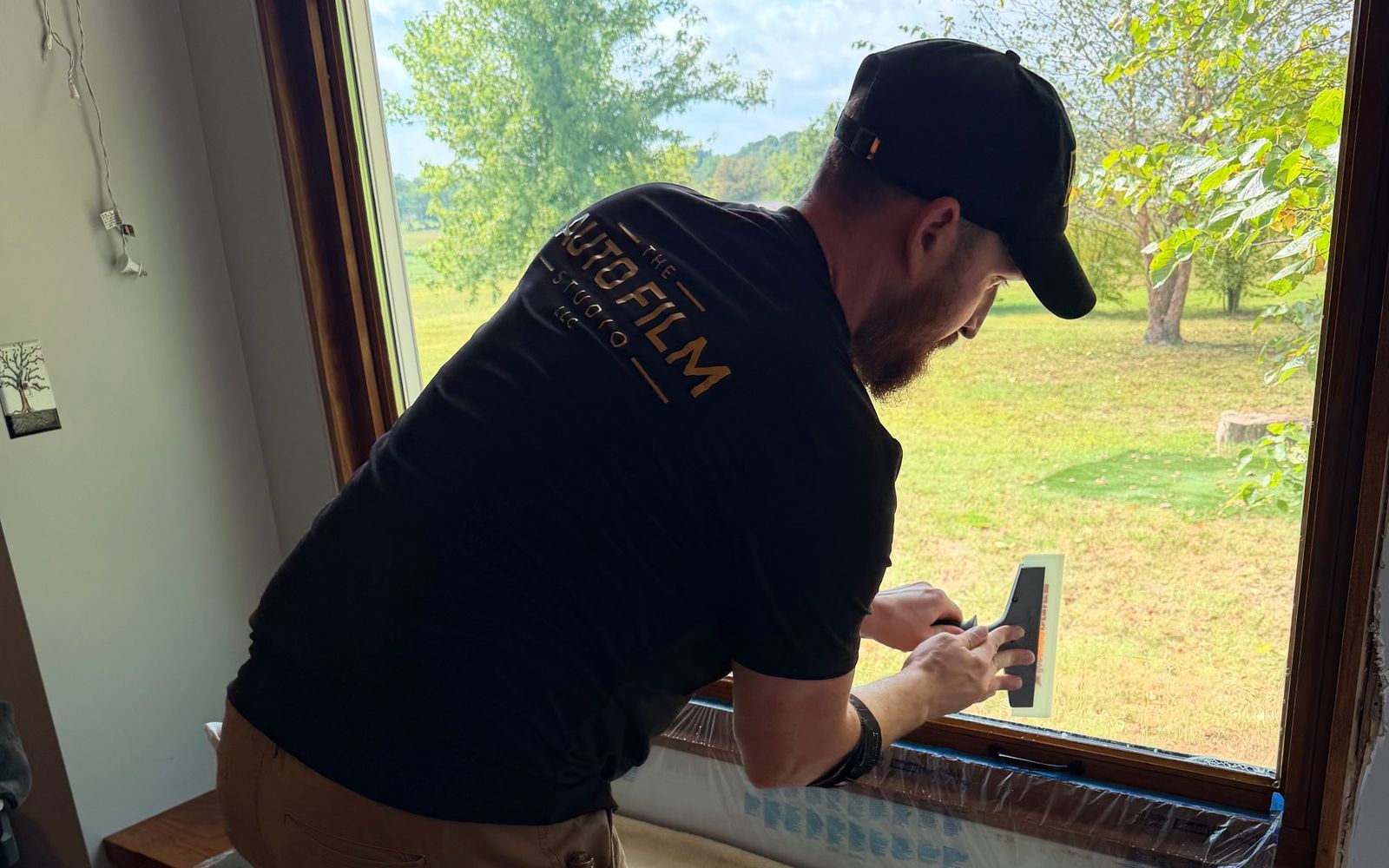 Auto Film Studio installer putting window film on a large picture window inside a home