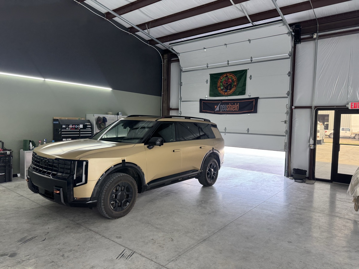 Wrapped Kia Telluride beside the Geoshield banner in the shop